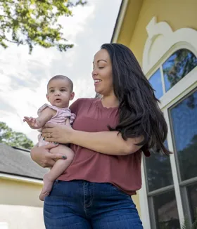 Ciera carries a baby girl, smiling fondly at her.  
